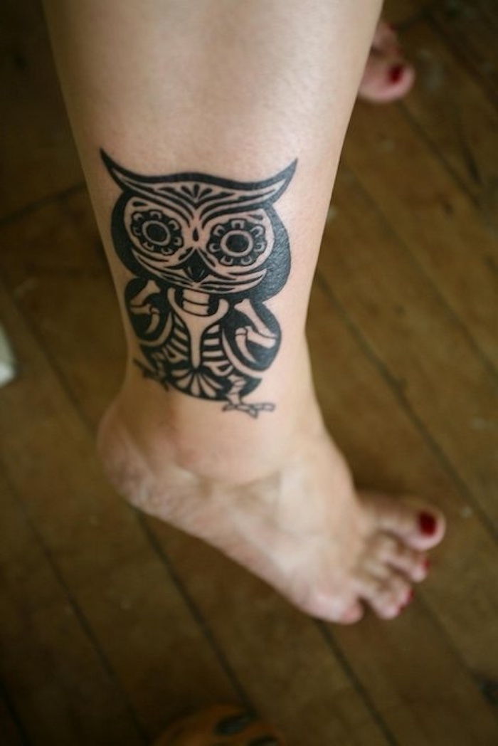 her er et ben med en svart tatovering med en svart ugle - ideen til en svart tatoveringsugle