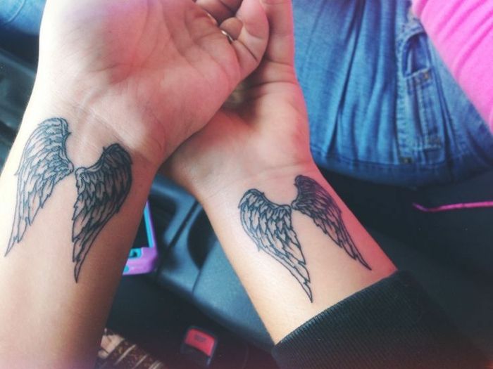 nekaj idej za tetovaže angelskih angelov - tukaj sta dve roki z majhnimi tetovaži angelskega krila z dolgimi črnimi peruti