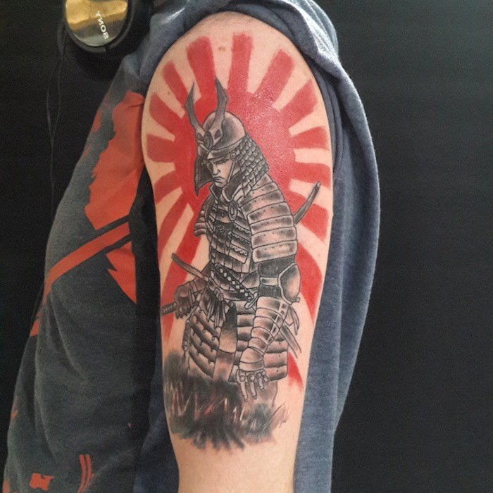 bojovník tetovanie, šedé tričko, červené slnko, muž s helmou a vybavenie
