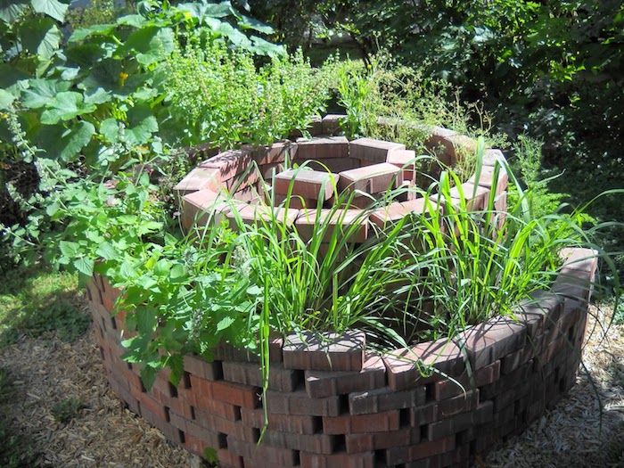 Aruncați o privire la această idee pentru o grădină cu o frumoasă spirală din plante, cu pietre și plante verzi