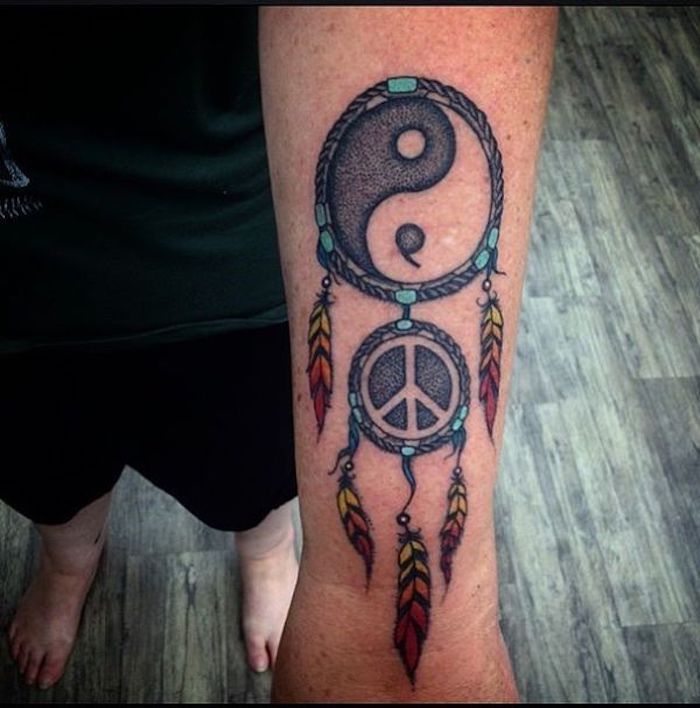yin e yang: idea per un grande tatuaggio al polso con un acchiappasogni e piume colorate