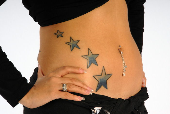 tatovering med fire blå store stjerner - en ung kvinne med stjerne tatovering - hånd med hvit hvit neglelakk og bryting
