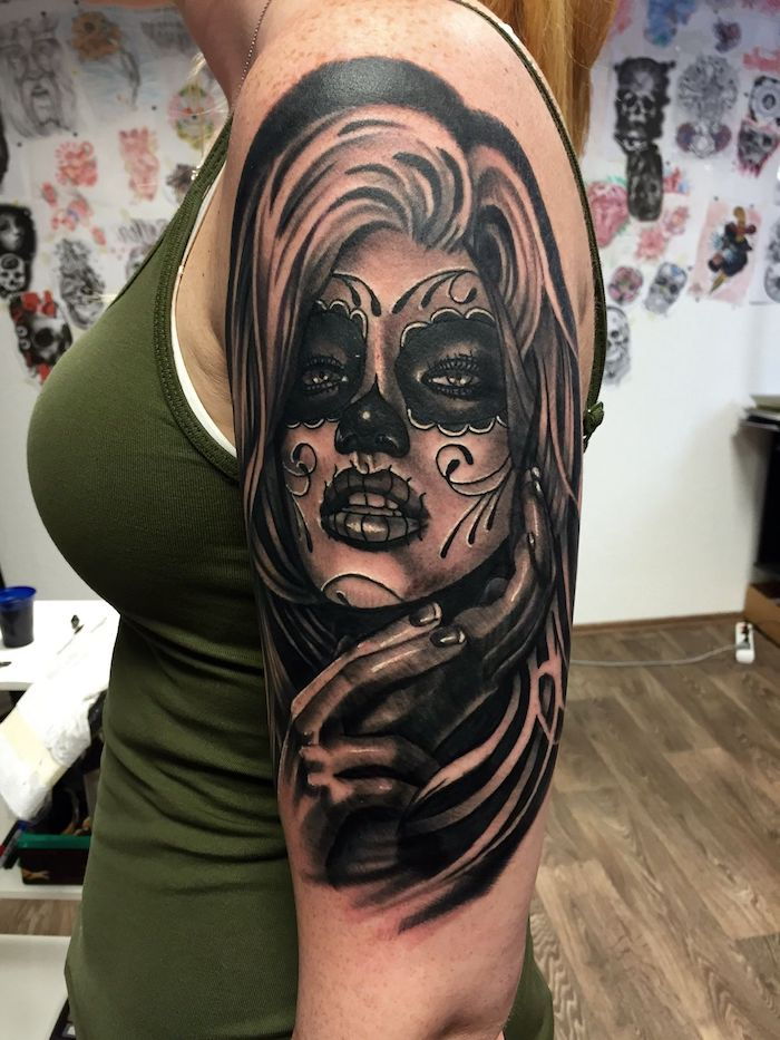 giovane donna con un grande tatuaggio nero con una catrina con labbra nere, occhi neri e un naso nero
