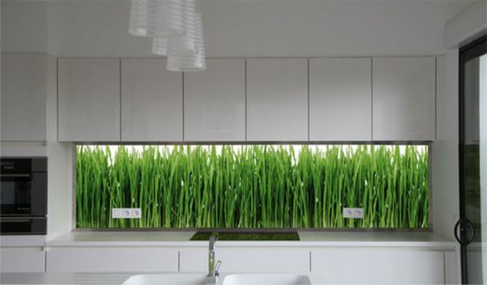 kuchnia z białymi szafkami i szklaną tylną ścianą z bambusem