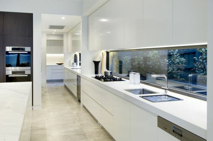 elegancka kuchnia w kolorze białym ze szklaną tylną ścianą z roślinami