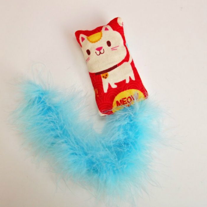 urobte bielu mačku ako obrázok na červenom vankúši a modrej stuhe - samotnej mačacej hračke