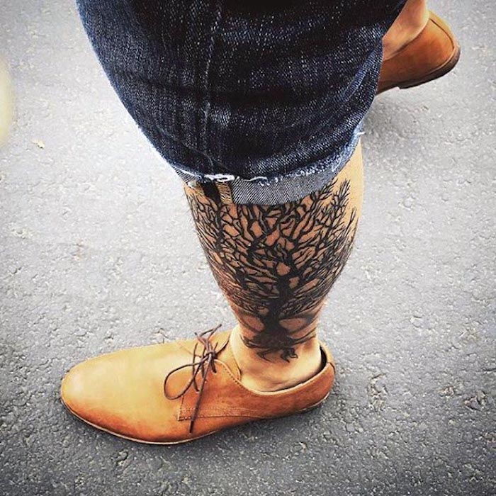 un tatuaj pe picior ca un copac al vieții, un bărbat cu pantaloni scurți de blugi și pantofi portocalii