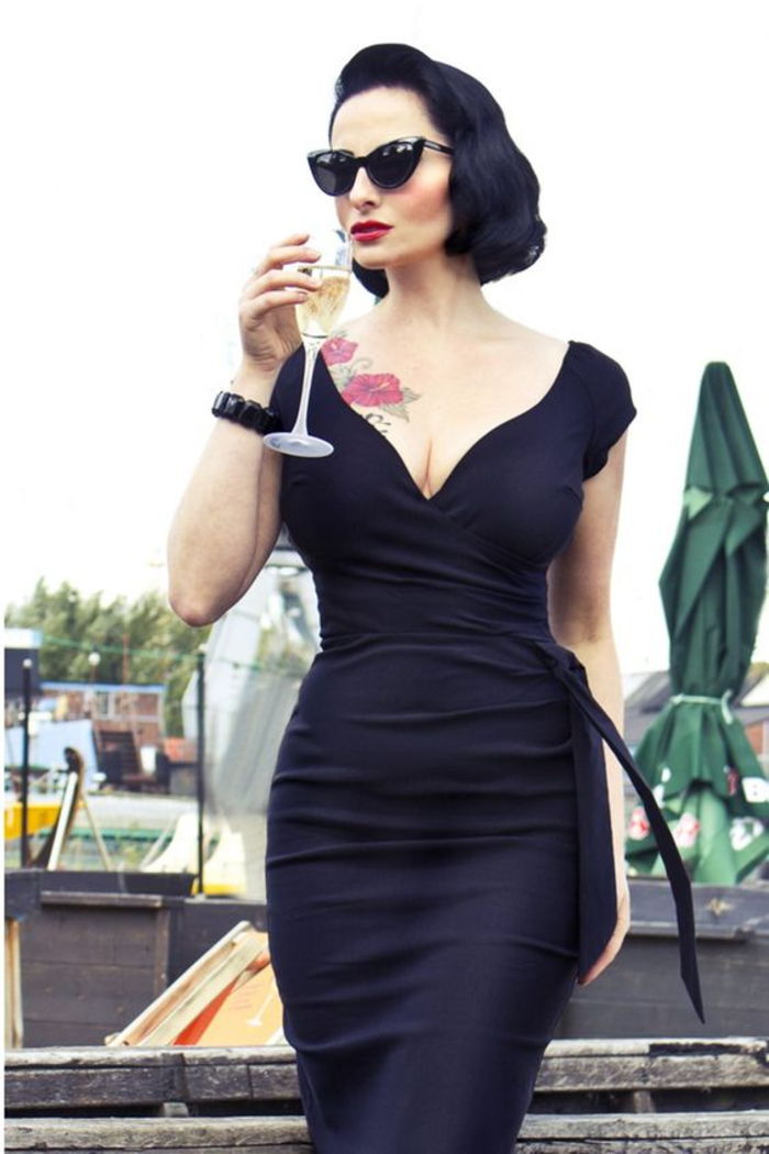 kjole i svart, med decollete, solbriller, armbånd, tatovering