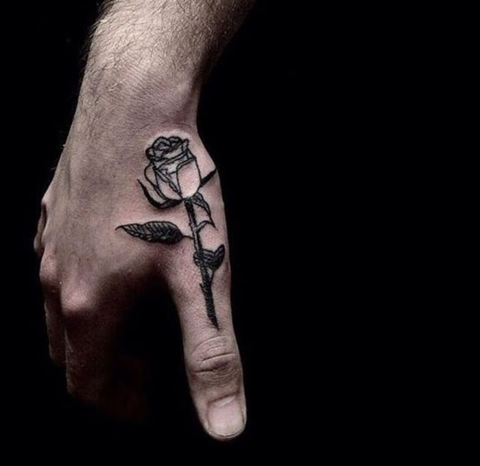 mano di un uomo con un piccolo tatuaggio rosa con foglie nere in mano - modello tatuaggio rose