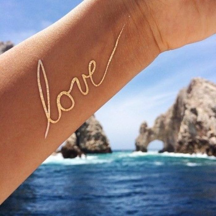 modelos de tatuagem mulheres amor com caneta dourada escrevendo tatuagem no braço mar harmonia romance