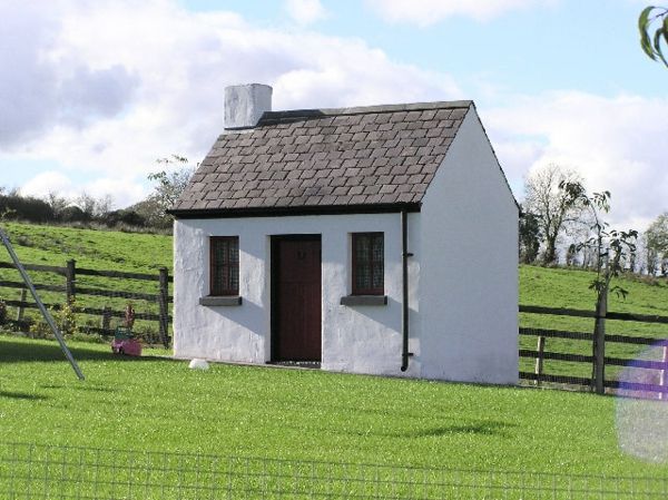 Små hus-bygg-grå-farger - omgitt av grønt gress