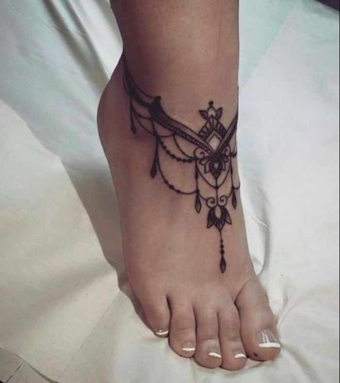 liten tatuering, fransk manikyr, tatuering i svart och grått på foten