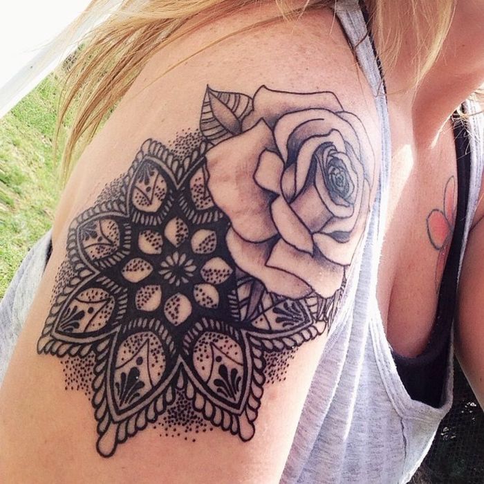 veľký šedý ruže s listom na ľavej strane a čierny mandaly s mnohými čiernymi bodkami, tetovanie na pravé rameno blondína s golblonden vlasmi, na sebe čierny top a kvetinovou tetovanie na ľavej strane hrudníka má
