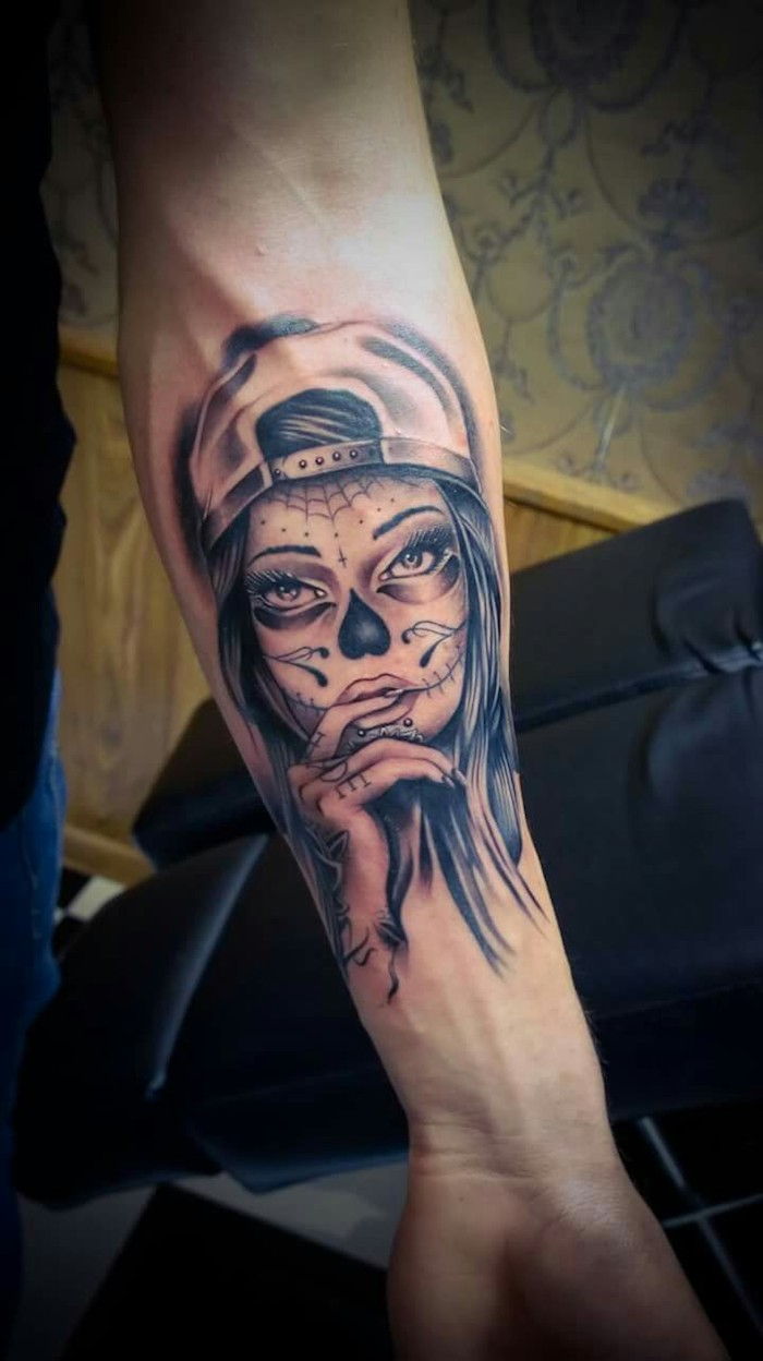 tatuaż la catrina - ręka z nieżyjącą młodą kobietą z czarnym nosem i kapeluszem oraz czarną pajęczyną