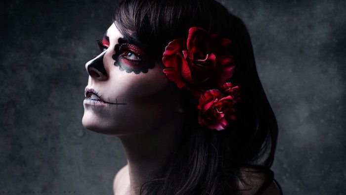 giovane donna con gli occhi neri e un naso nero e tre grandi rose rosse - trucco la catrina