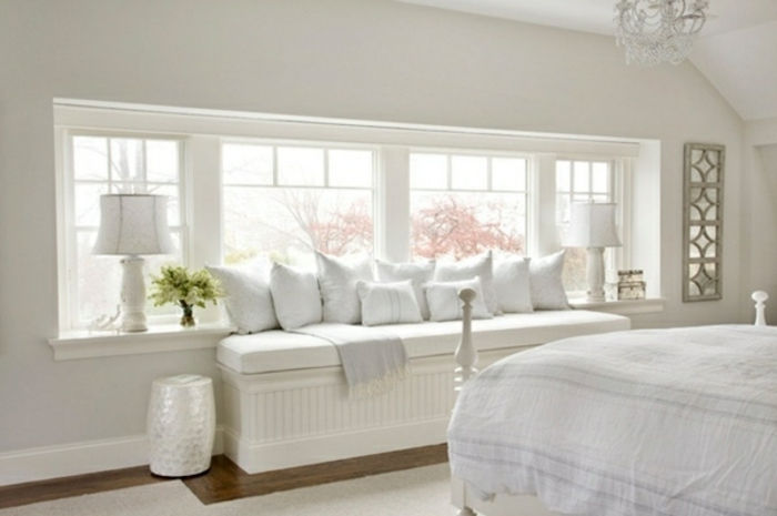 witte slaapkamer zittend op de vensterbank lampen en kussens