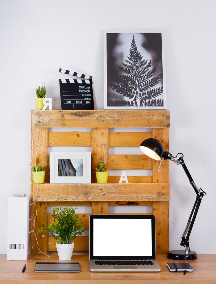črna luč, polica starih palet in črne slike z belo okvirji za slike in rumene vaze z malo zelenimi rastlinami