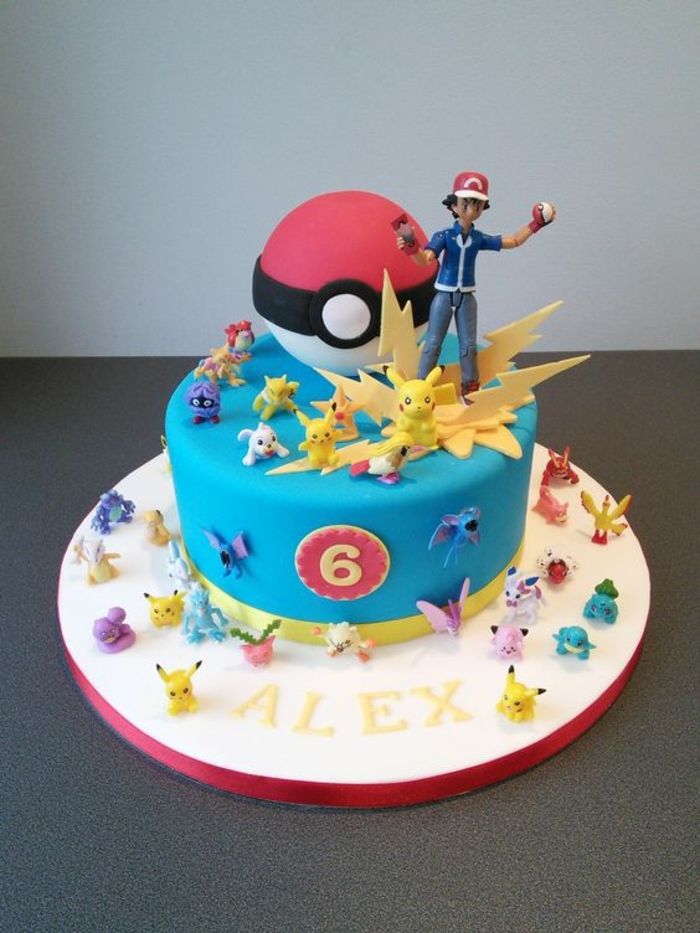 una torta di pokemon blu con lampi gialli, una pokeball rossa, piccoli esseri pokemon diversi, pikachu, un ragazzo con un berretto rosso