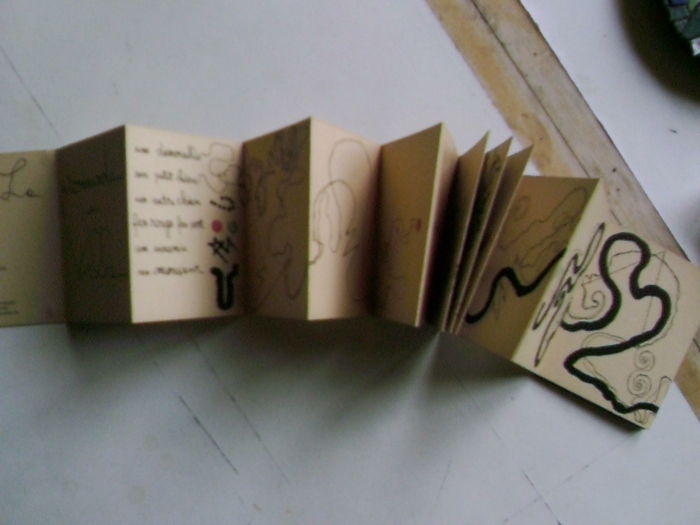Leporello gjør ut av papp med påskrifter og små bilder i brun farge