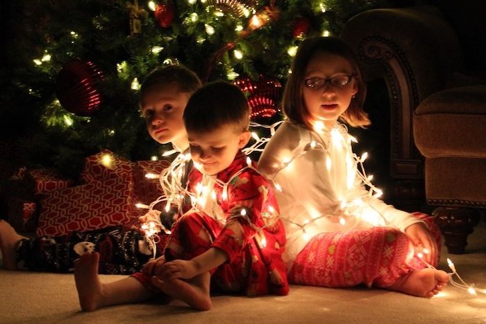 rolig jul tre söta barn leker med en feljus framför julgranen