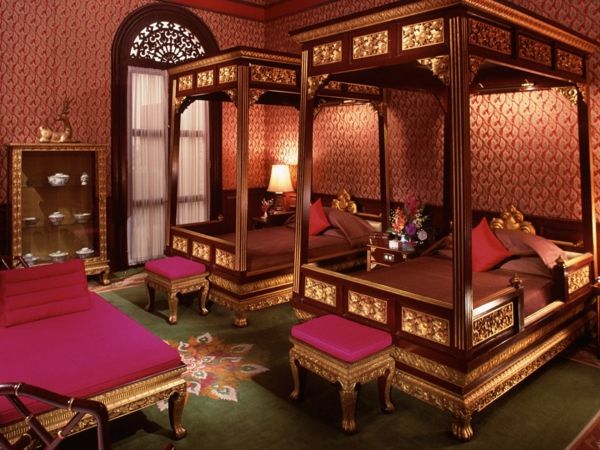 två rymliga sängar med kolumner i lyxigt orientaliskt sovrum