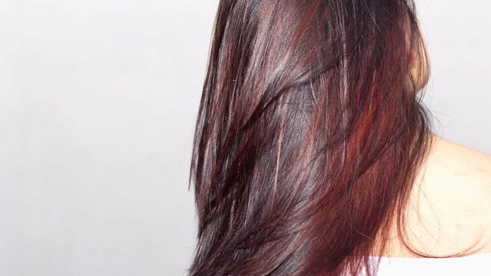 cabelo brilhante e vibrante com um matiz de cor de mogno escuro e reflexos vermelhos nos comprimentos, ombro branco de blusa, imagem com um fundo cinza claro