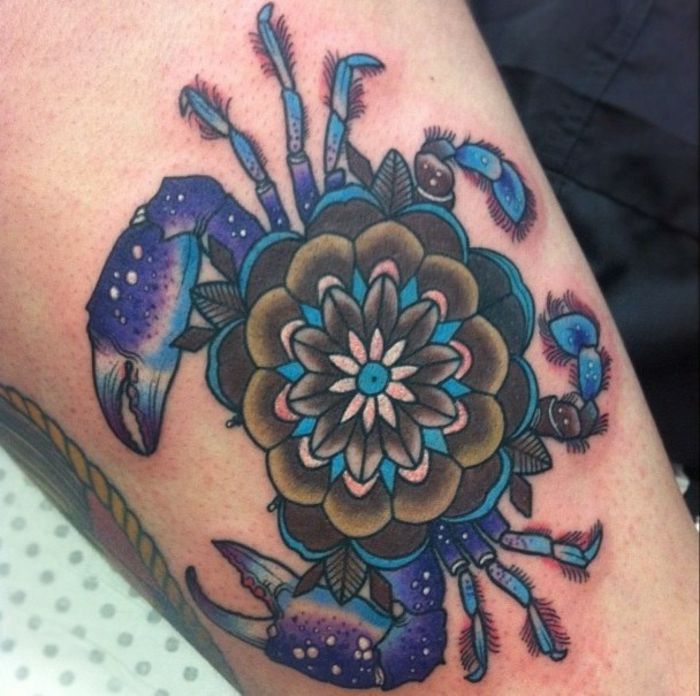 grande tatuaggio del segno zodiacale Cancro con un fiore al centro, tatuaggio zodiacale blu-viola con un piccolo mandala, tatuaggio con motivo floreale