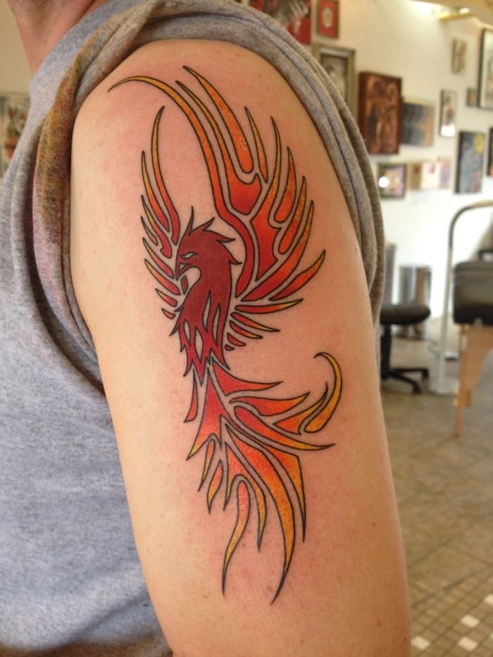 Rankų su raudona tatuiruotė su dideliu raudonu plaukiojančiu feniiksu su dviem sparnais su raudonomis, oranžinėmis ir geltonomis ilgais plunksnomis