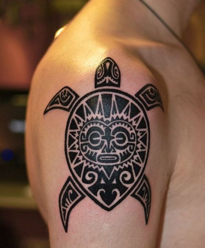 mladenič s črno tetovažo z veliko črno želvico in soncem s črnimi očmi - tattoo roko Maorie