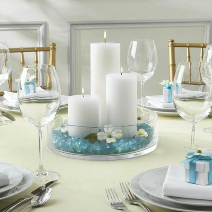 Bir masa dekorasyonu olarak deniz yaz dekorasyon beyaz mumlar ve turkuaz taşlar