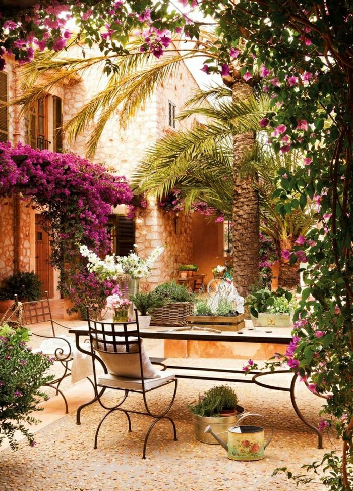 Mediterrâneo jardim de flores rosadas cadeiras mesa-ferro forjado palma vasos de flores regador