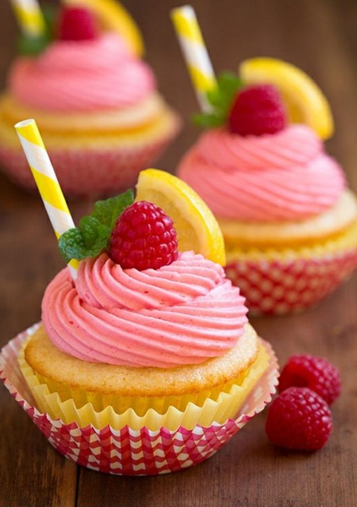 små muffins dekorert med rosa krem, bringebær, peppermynte og sitron