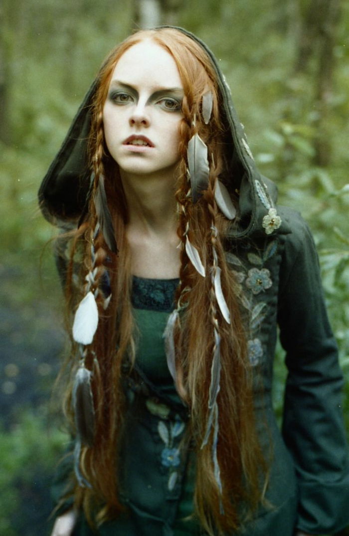 o vrăjitoare în pădure cu pene în părul părului ei roșu, rochie verde - coafuri medievale