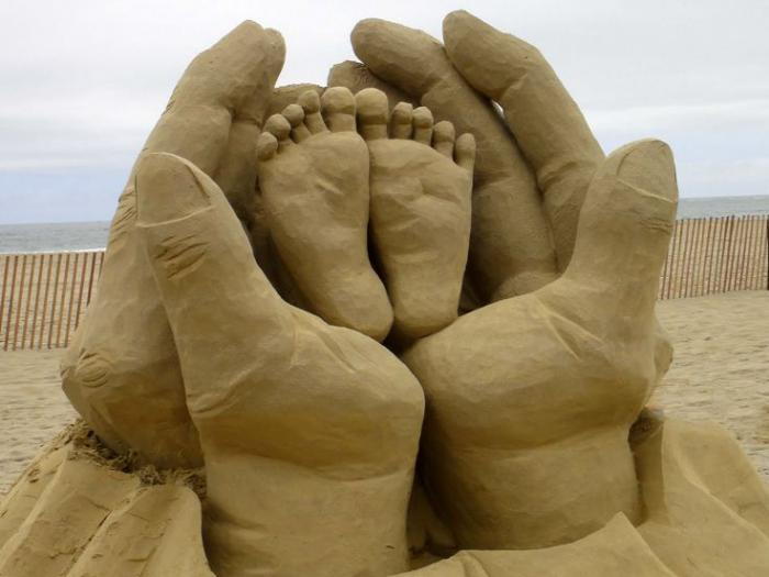 Moderna skulptura iz peska otroške noge-v-roke-v-oče