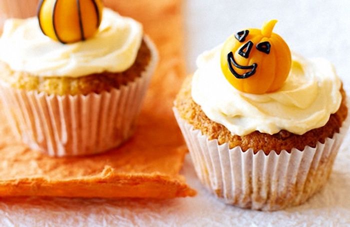 Cozimento de Halloween, cupcakes decorados com creme e abóboras de fondant