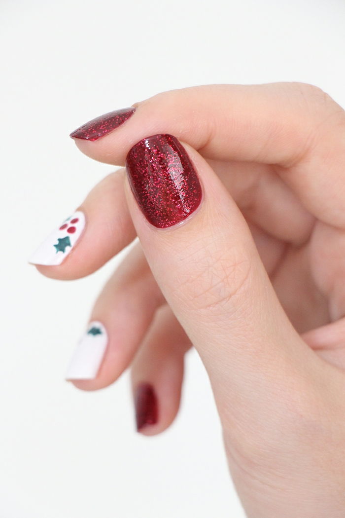 Idé för vinterspik, mistelte på en vit bakgrund, rödglans nagellack, oval nagelform