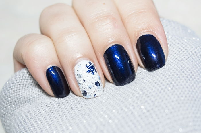Vinterns naglar, mörkblå snöflingor på en vit bakgrund, mörkblå nagellack, vinklig nagelform