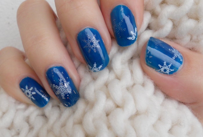 Witte en zilveren sneeuwvlokken op donkerblauwe grond, ronde nagelvorm, winter nail art design