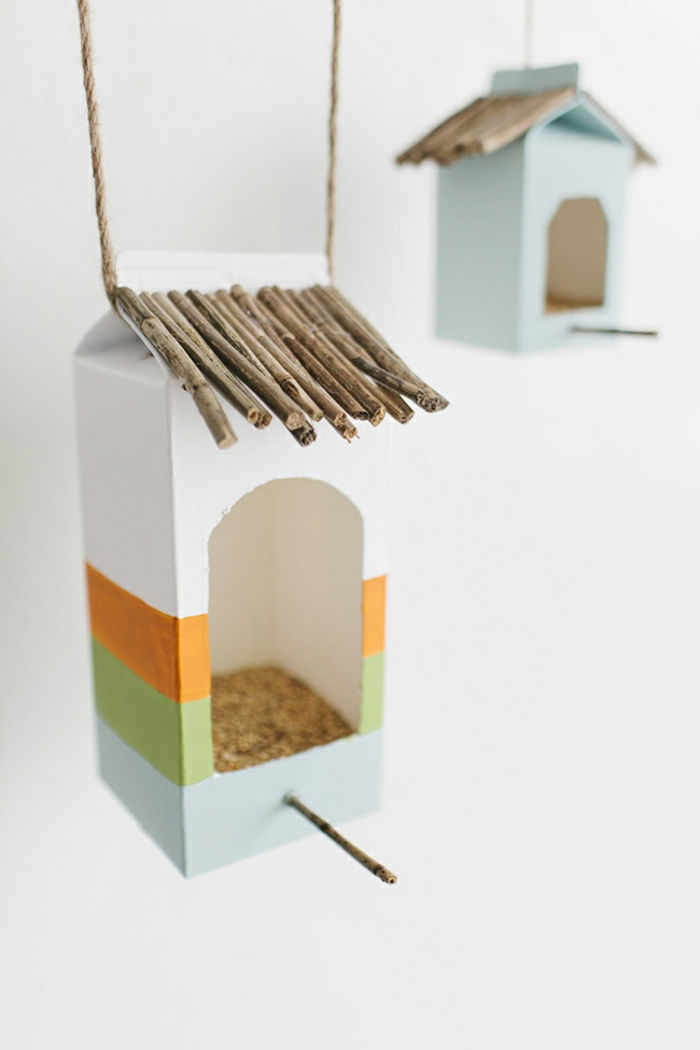 Birdhouses de funileiro feitos de papelão de leite, encher com sementes e sementes de girassol, enfiar em palitos