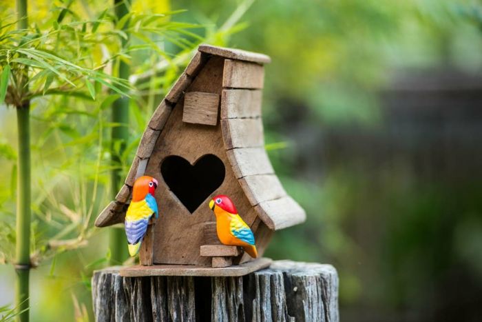 Caixa de aninhamento feita de madeira, janela como um coração, dois papagaios de cerâmica coloridos, bela decoração para o seu jardim ou varanda