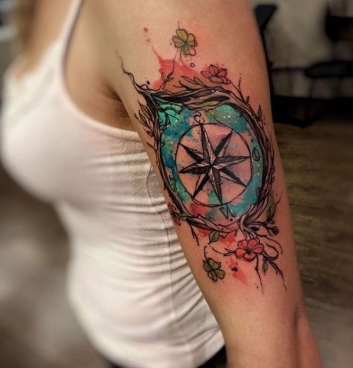 to pomysł na tatuaż kompasowy dla kobiet - kompas i małe zielone i czerwone kwiaty