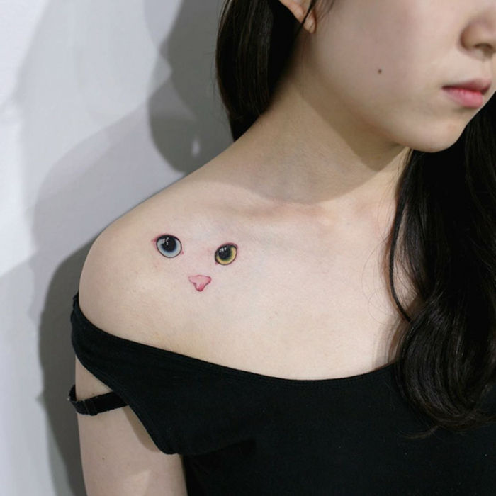 Ideea pentru un tatuaj frumos de pisici pe umăr pentru o femeie tânără - aici este o pisică cu ochi verzi și un nas roz