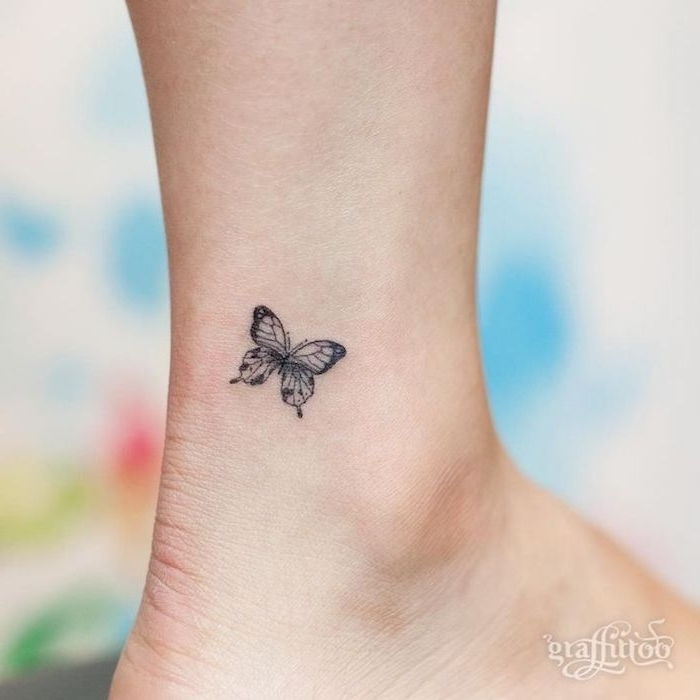 en søt liten svart mini liten tatovering med en vakker svart flygende sommerfugl på beinet