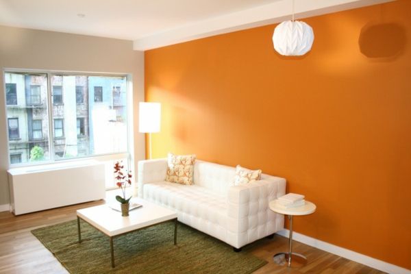 pomarańczowa ściana w salonie z białymi meblami i nowoczesnym wzornictwem