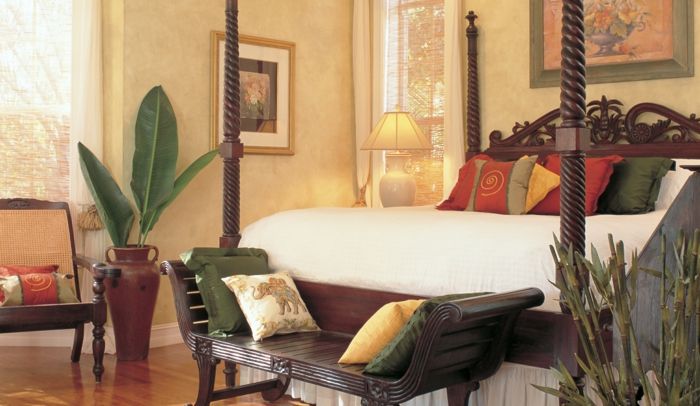 orientalisk inredning stor säng med många kuddar och exotiska designpalmer blommor naturligtvis