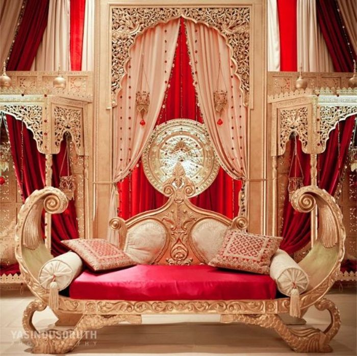 Anlegg i Aladin stil - dekk med tre ben, malt i gull farge, designer kaffe heltre, rundde puter med dusker, veggbelegg med carving, rund veggdekorasjon av gull, lange røde hardt fallende gardin