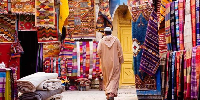 człowiek w lekkich ubraniach na rynku Agadiru dla orientalnych tkanin, dywanów i zasłon