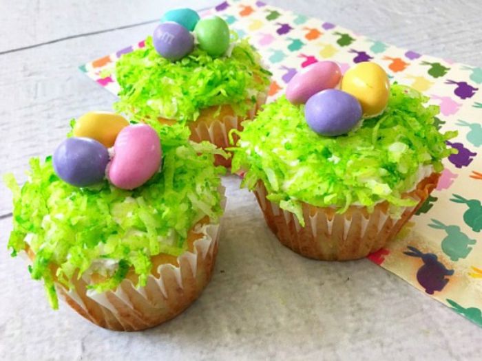 Cupcakes som grønt gress fullt av fargerike egg i rosa, lilla og gul farge