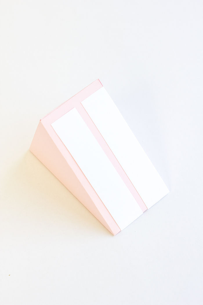 Fällbara lådor - en bit tårta i papper, de vita ränderna på en rosa bakgrund