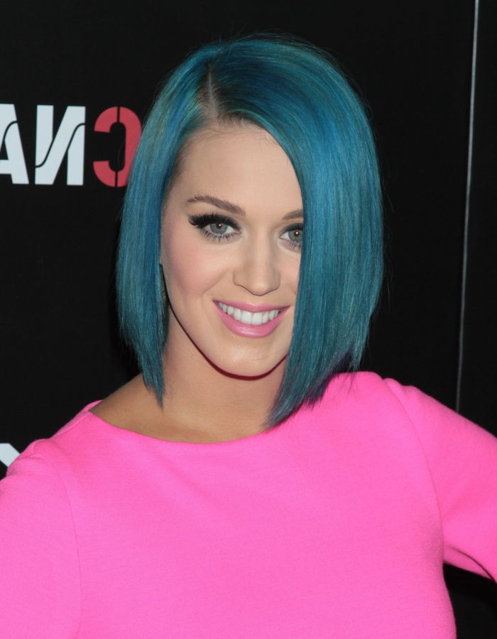 Katy Perry com penteado bob azul, lábios rosa suaves, rímel preto, roupa em cores brilhantes